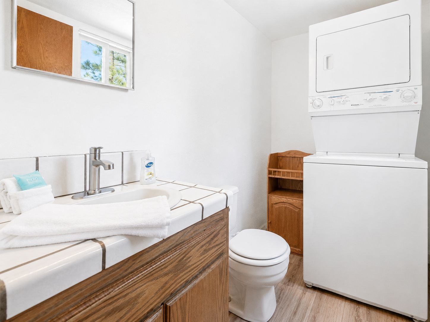 Un baño moderno con lavamanos, inodoro y lavadora integrada.