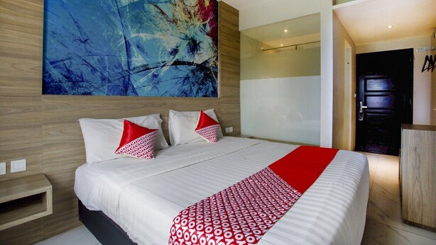 A modern hotel room with a large abstract painting, a bed with white bedding and red accents, a wooden headboard, and a large window. - Luxury Deluxe DBL Escape W/ Free WiFi and Parking (Bekasi)
