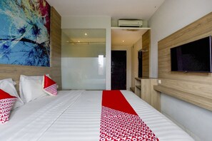 A hotel room with a bed, a TV, a large abstract painting, and a shower area.