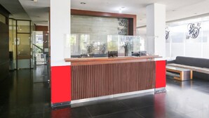 A reception desk with a glass partition, a red and white color scheme, and a modern interior design.