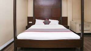 A four-poster bed with a wooden frame, white bedding, and a red accent.