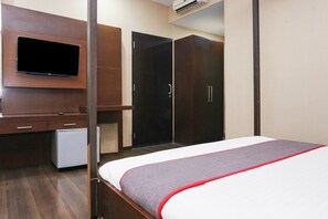 Ein Hotelzimmer mit Bett, Wand-Fernseher, Schreibtisch mit Stuhl und Kleiderschrank.