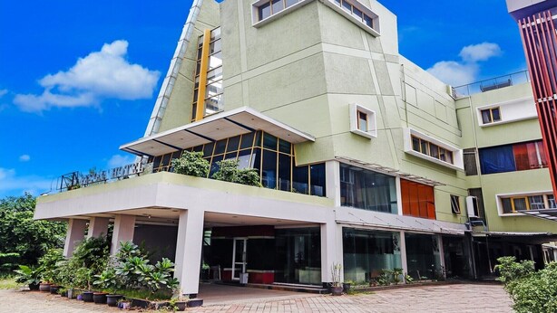 A modern hotel with a flat roof, large windows, and a covered entrance area.