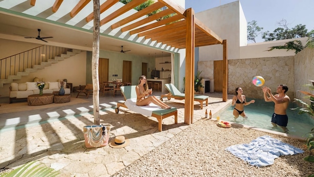 Un espace de vie extérieur moderne comprenant une piscine, des chaises longues et un patio couvert.