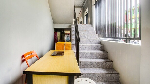 A narrow stairway with a wooden desk and chair, a laptop, and a small stool. - Cozy Double Escape W/ Free WiFi and Parking (Bandar Lampung)