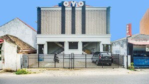 A building with a sign 'OYO' at the top, a gated entrance, and a parked car in front. - Cozy Double Escape W/ Free WiFi and Parking (Bandar Lampung)