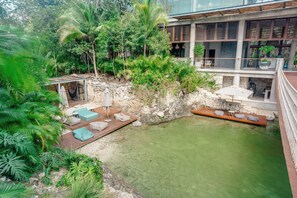 A modern house with a pool, surrounded by lush greenery. - Modern 1BR at Xalet Luxury Condos | Cenote & Pool (Tulum)