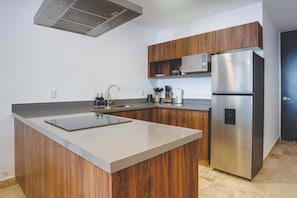 A modern kitchen with wooden cabinets, a stainless steel refrigerator, and a built-in microwave. - Luxury 2BR Retreat with Private Pool & Spa (Tulum)