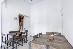 Une salle de conférence avec une grande table en bois, six chaises et une porte avec des rideaux.