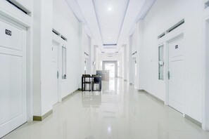 A long, narrow hallway with white doors numbered 109 and 104, leading to a bright room at the end.