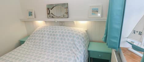 A bedroom with a bed, a nightstand, a dresser, a mirror, and a framed picture on the wall.
