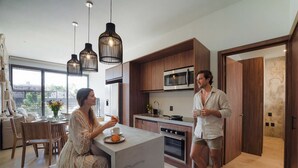 Een moderne keuken met houten kastjes, een magnetron en een eethoek met een tafel en stoelen.
