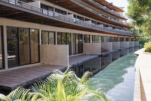 A modern hotel with a long pool, wooden deck, and multiple balconies. - Modern 2BR Apartment with Pool & Gym (Tulum)