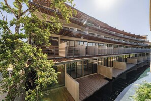 Ein modernes Hotel mit mehreren Balkonen, einem Pool und einer Holzterrasse.