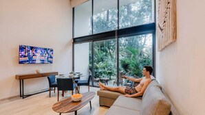 A modern living room with a sofa, a coffee table, and a TV mounted on the wall. - Luxury Two-Level Loft in Tulum with Pool & Gym (Tulum)