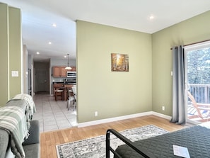 A room with a bed, a sofa, a dining area, and a kitchen in the background.