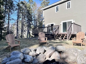 A house with a deck, two Adirondack chairs, and a stone wall.