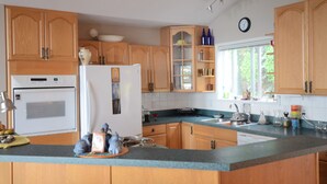 A kitchen with wooden cabinets, a refrigerator, a stove, and a window. - Serenity.  So peaceful! .A place to retreat on kootenay lake (Ainsworth)