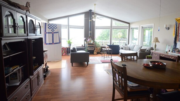 A spacious living area with a dining table, a sofa, and a kitchen area with cabinets. - Serenity.  So peaceful! .A place to retreat on kootenay lake (Ainsworth)
