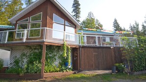 A two-story wooden house with a balcony, a fenced garden area, and a wooden deck. - Serenity.  So peaceful! .A place to retreat on kootenay lake (Ainsworth)