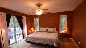 A bedroom with a bed, two bedside lamps, a ceiling fan, and a view of the outdoors through a sliding glass door. - Serenity.  So peaceful! .A place to retreat on kootenay lake (Ainsworth)