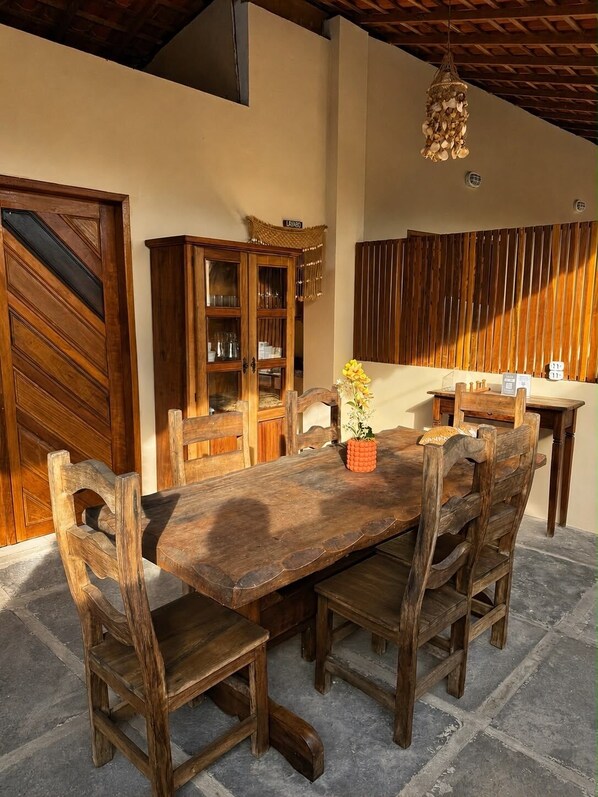 A wooden dining table with chairs, a cabinet, and a hanging light fixture.