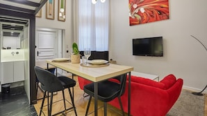 Een moderne keuken met een eethoek, een rode bank en een televisie aan de muur.