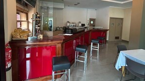 Een keuken met een rode aanrecht, barstoelen, een televisie en een koelkast.