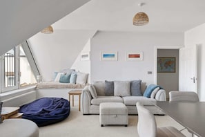 Ein modernes Schlafzimmer im Loft-Stil mit schrägem Dach, einem großen Fenster, einer Couch, einem kleinen Tisch und einem Sitzsack.