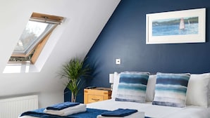Ein Schlafzimmer mit Bett, Fenster, Pflanze und einem Bild an der Wand.