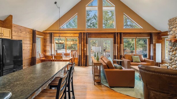 A spacious loft-style room with a large kitchen, dining area, and seating area, featuring high ceilings and large windows.