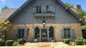 A two-story building with a stone foundation, a gabled roof, and a front entrance with a door and windows.