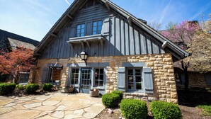 A stone building with a gabled roof, large windows, and a stone pathway leading to the entrance. - Pere Marquette Lodge and Conference  (Grafton)