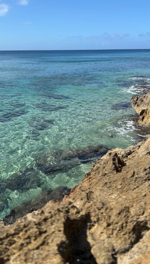 A rocky coastline with clear water and a view of the ocean. - Borinquen Beach Retreat - Apt 3 | Minutes to Beach (Borinquen)
