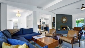 Una sala de estar moderna con un sofá azul, sillones de cuero, una mesa de centro y una chimenea.