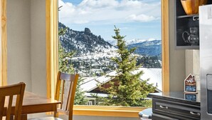 A balcony with a wooden chair, a small Christmas tree, and a view of snow-covered mountains. - Estes Park retreat w/ hot tub, fireplace, king suite (Estes Park)