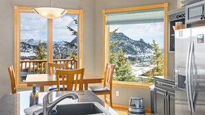 A kitchen with a view of mountains, a dining area with chairs, a sink, and a refrigerator. - Estes Park retreat w/ hot tub, fireplace, king suite (Estes Park)
