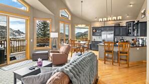 A spacious living area with a sofa, chairs, a coffee table, and a view of a deck.