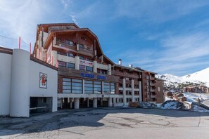 Ein mehrstöckiges Hotel mit einer Skipiste im Hintergrund.