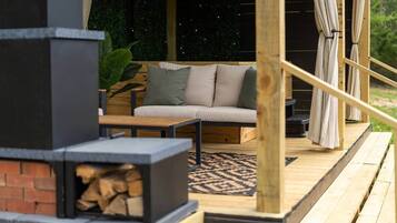 Une terrasse en bois avec un canapé et une cheminée.