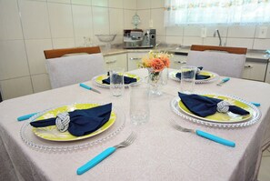 Uma mesa de jantar posta com pratos, guardanapos, talheres e um vaso de flores.