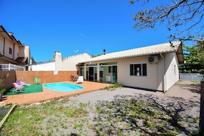 Um imóvel residencial com piscina, área de estar no pátio e garagem separada.