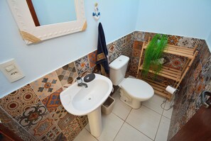 Casa de banho com lavatório branco, sanita e espelho.