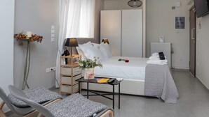 A modern bedroom with a bed, bedside table, lamp, and a small table with a vase of flowers. - The Athenian Penthouse Studio - An Urban Haven (Athens)