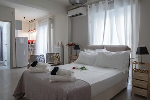 Ein Schlafzimmer mit Bett, Nachttischen, einer Lampe, einem Heizkörper und einem Fenster mit Vorhängen.