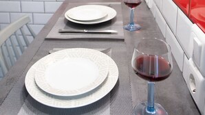 A dining table set with plates, cutlery, and wine glasses, with a red and white tiled backsplash and a framed picture on the wall. - The Athenian Penthouse Studio - An Urban Haven (Athens)