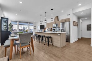 Une cuisine moderne dotée d’un îlot central, de tabourets de bar et d’un coin repas avec une table et des chaises.