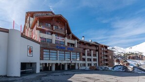 Un hôtel à plusieurs étages avec une piste de ski en arrière-plan.