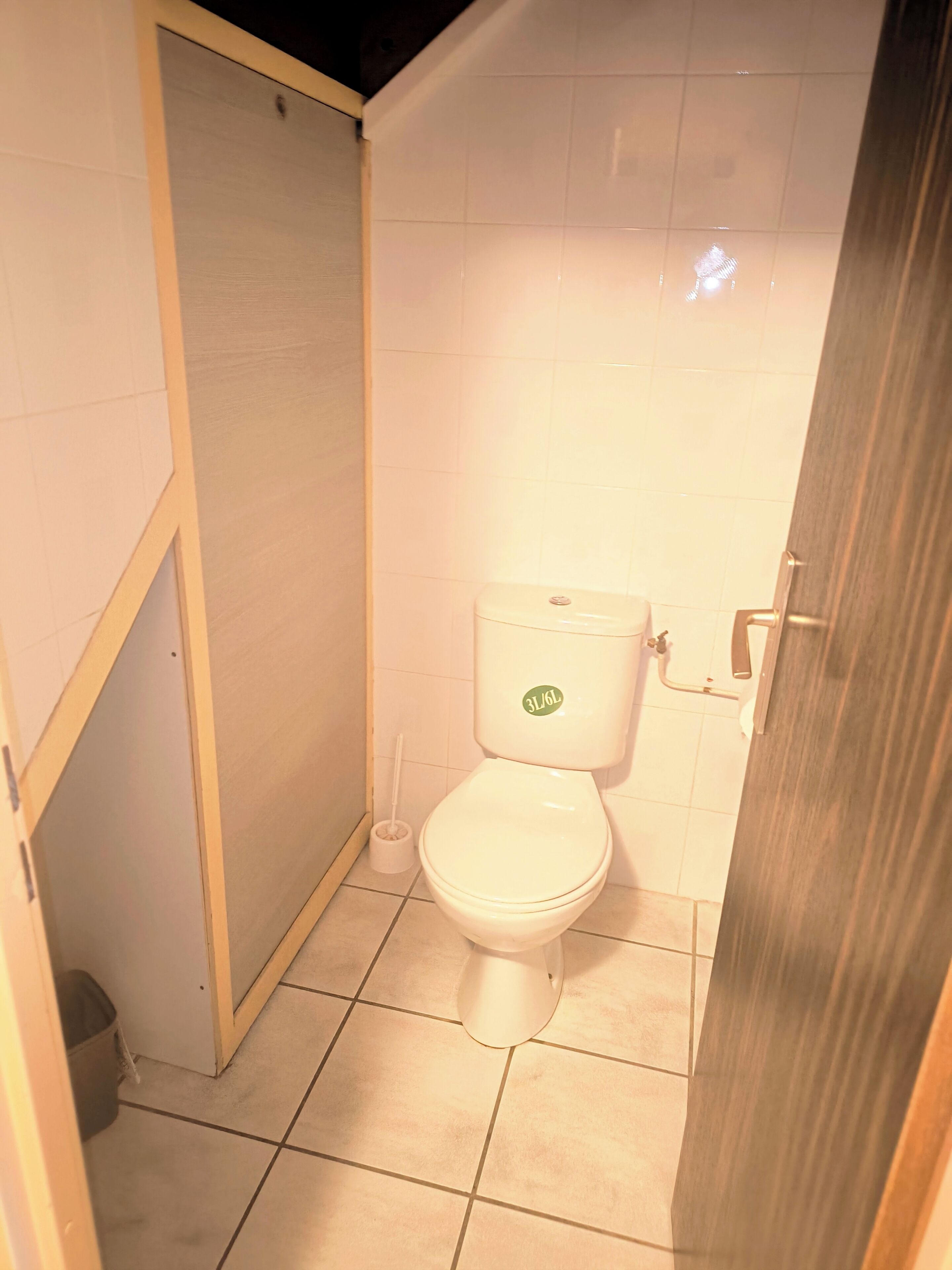 Une petite salle de bain fermée, équipée de toilettes, d’un bidet et d’une poubelle.