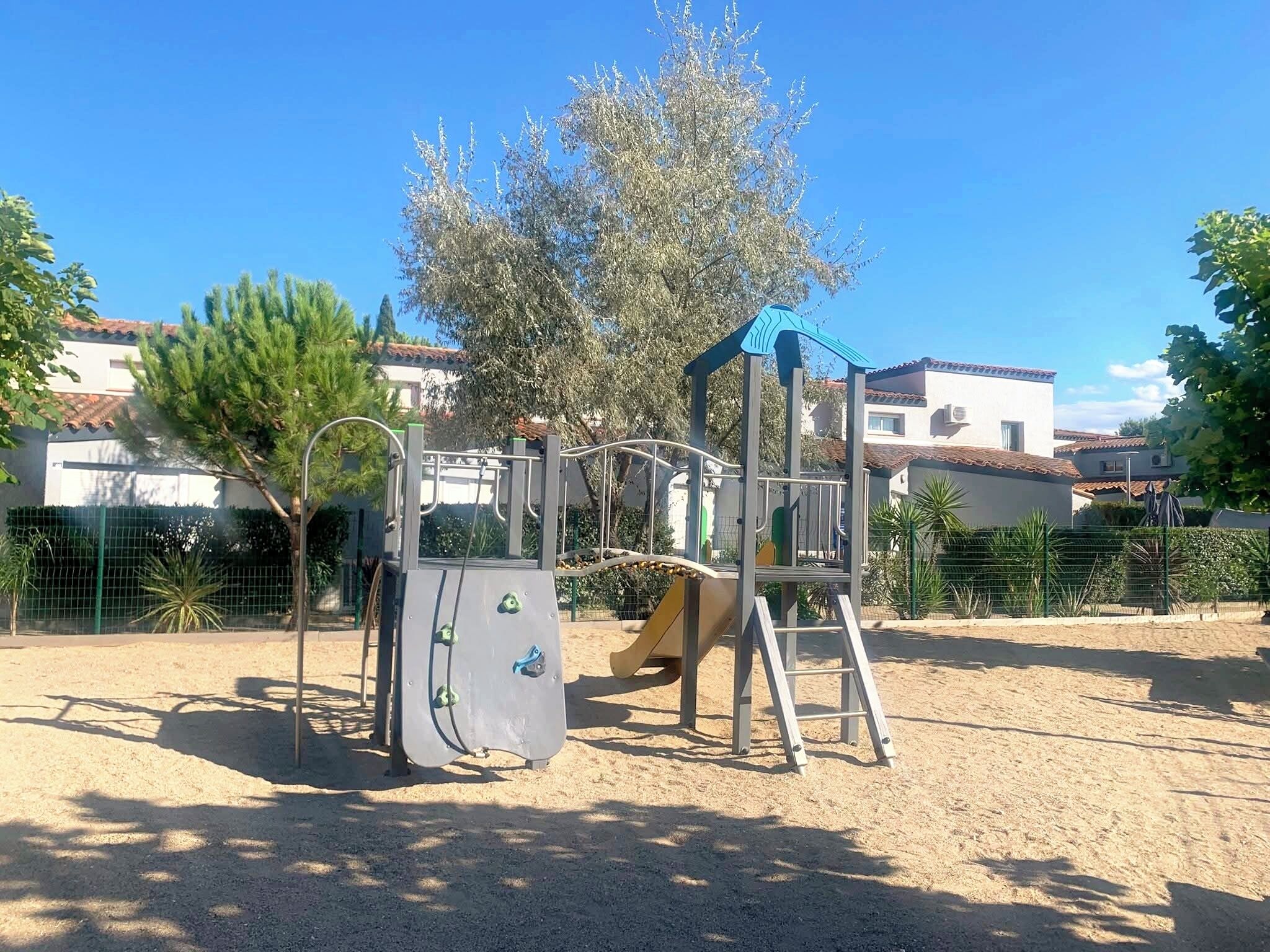 A playground with a climbing structure, a slide, and a ladder.